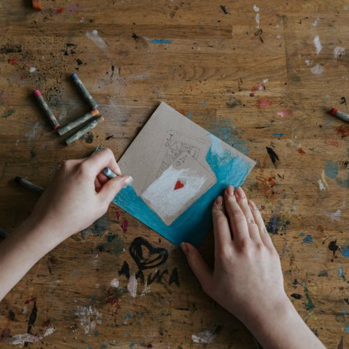 A Person Coloring a Drawing of Playing Cards on a Paper